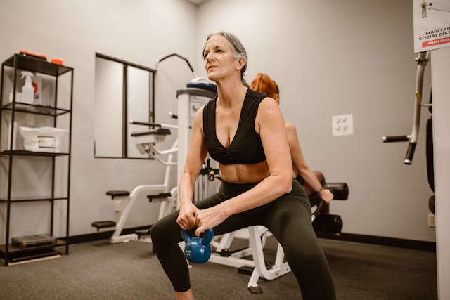 Woman Squatting While Holding a Kettle Bell