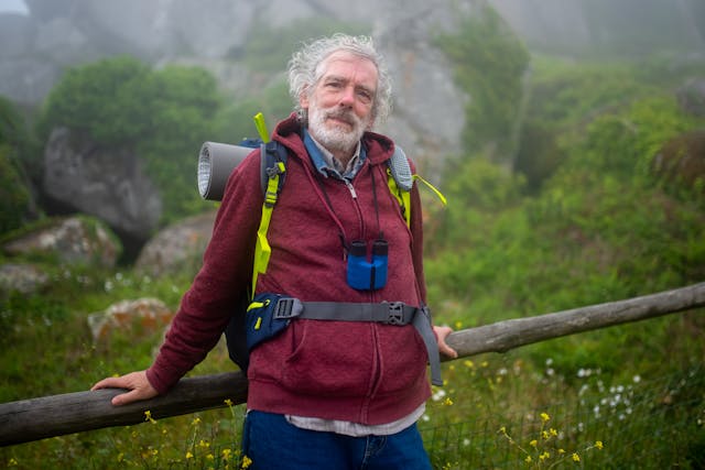 Man in Red Jacket Standing Near Brown Wooden Fence