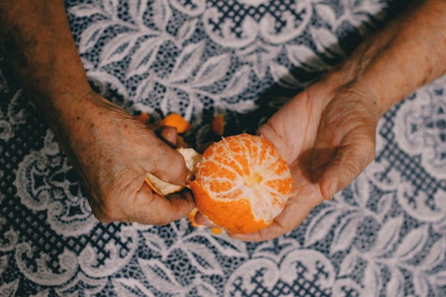 senior holding an unwrapped orange