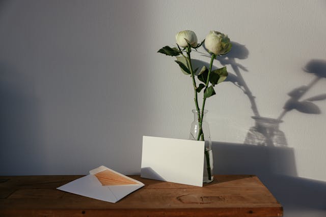 Envelopes and a Vase of White Roses on a Wooden Table