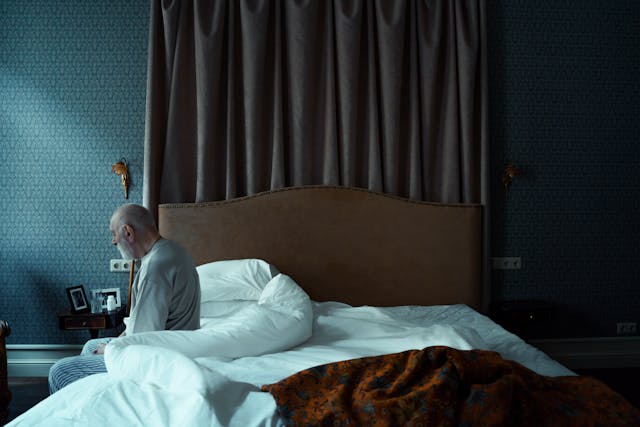 Elderly Man Sitting on a Bed