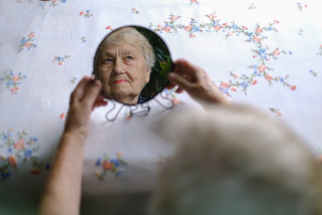 Pensive elderly woman reflecting in mirror