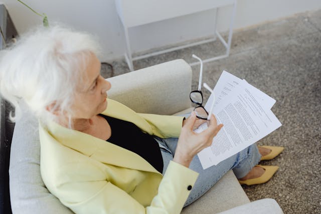 An Elderly Woman in Yellow Blazer Holding Documents