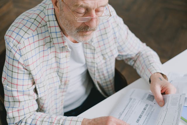 Elderly man in glasses carefully examines documents