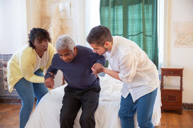 An elderly man receiving assistance from caregivers
