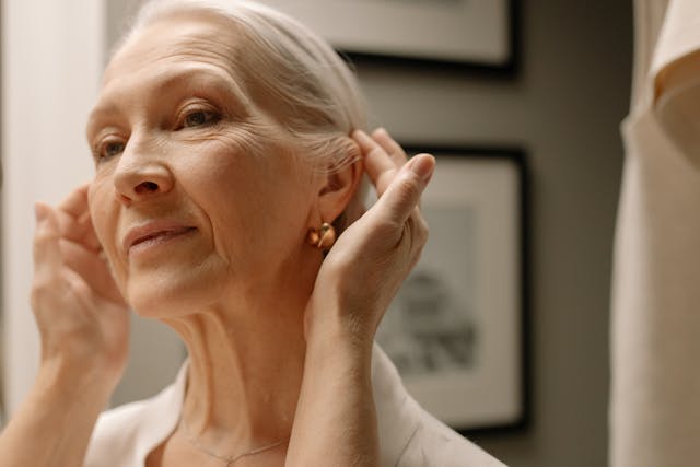 Close-up of an elderly woman adjusting earrings