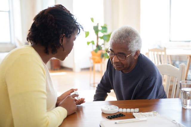 A caregiver and an elderly man discuss medication